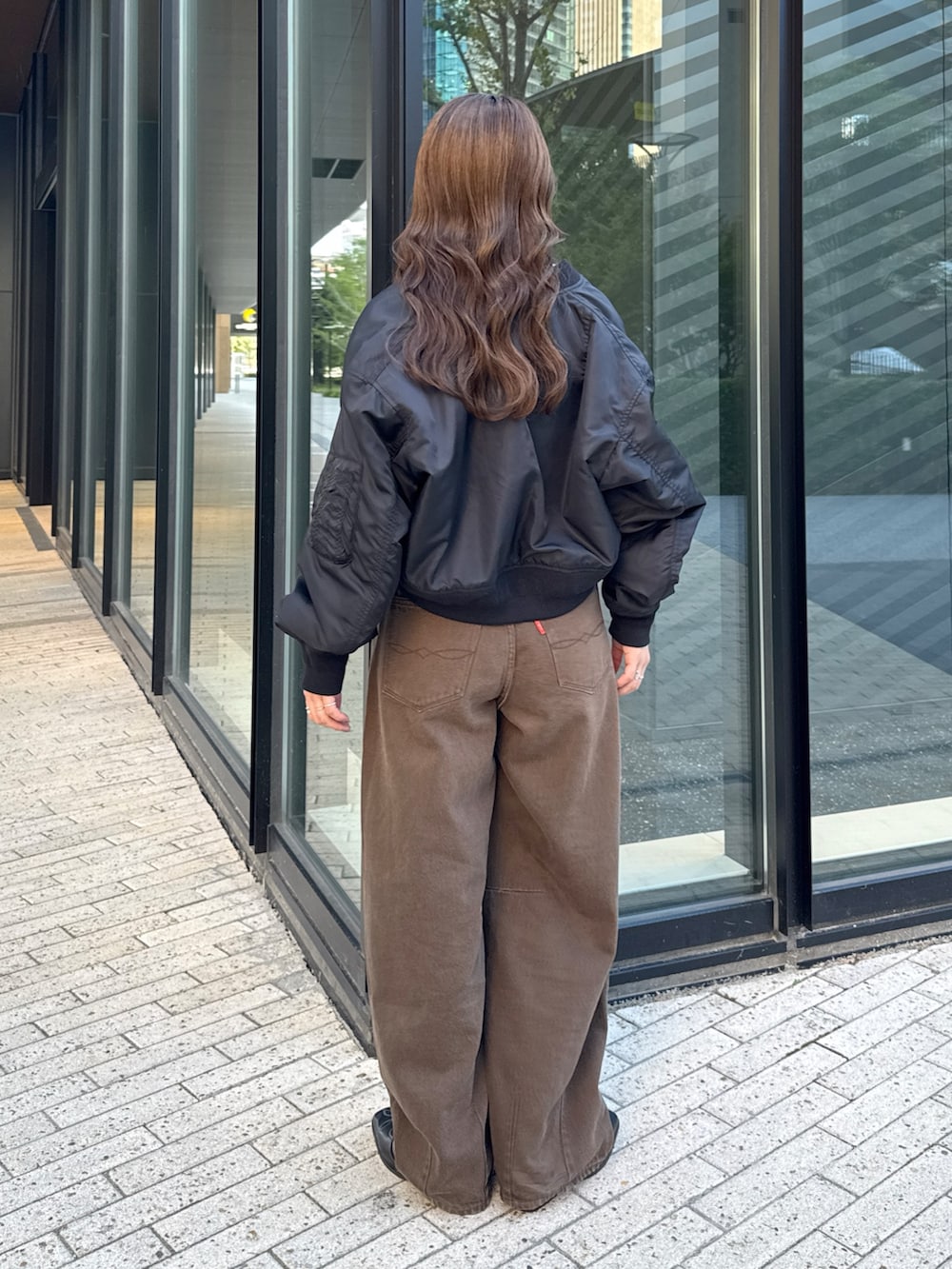 ブラウン系のデニムパンツ、ホワイト系のTシャツ/カットソー、ブラック系のMA-1を着用したレディースの秋コーディネートの4枚目の写真