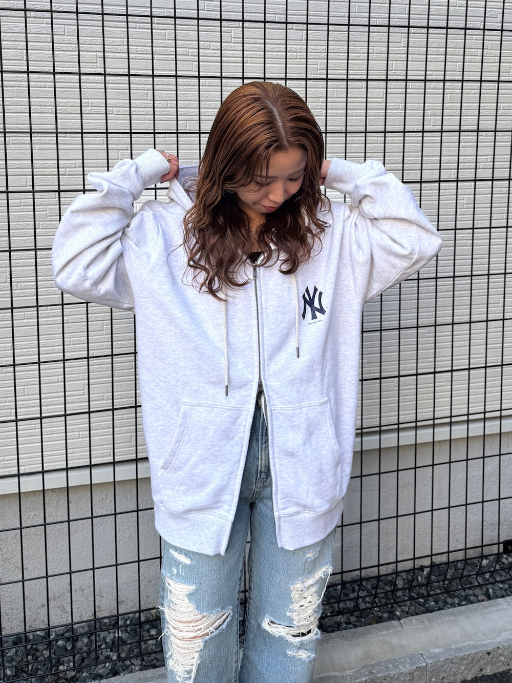 グレー系のパーカー、ブルー系のデニムパンツ、ブラック系のパンプスを着用したレディースの春コーディネートの7枚目の写真