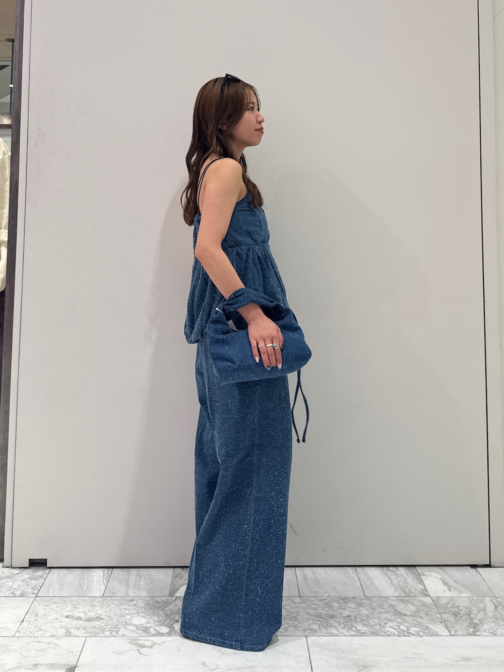 ブルー系のチューブトップ、ブルー系のデニムパンツ、ブルー系のハンドバッグを着用したレディースの春コーディネートの2枚目の写真