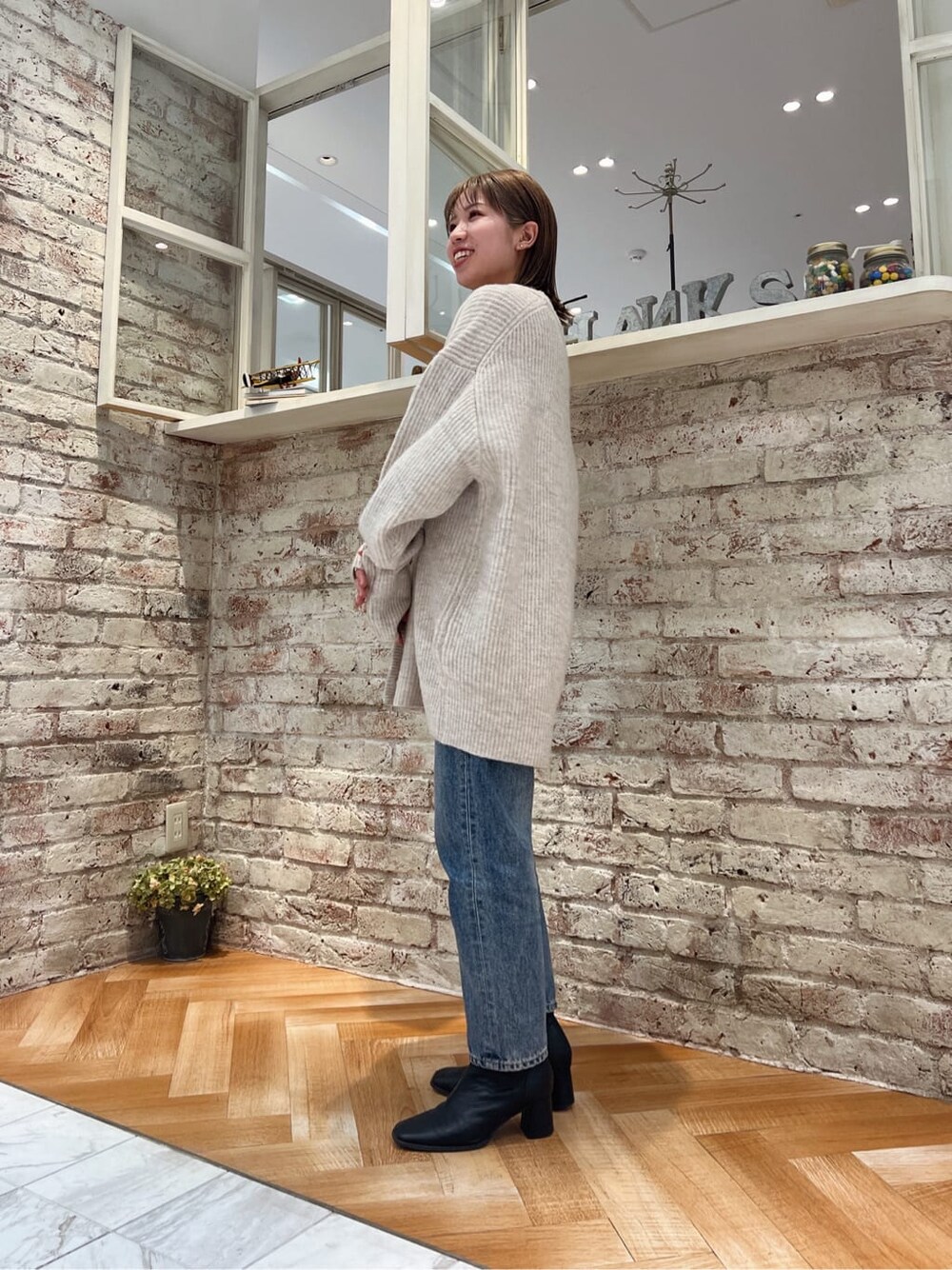 ブラック系のブーツ、ブルー系のデニムパンツ、ホワイト系のカーディガン/ボレロを着用したレディースの秋コーディネートの7枚目の写真
