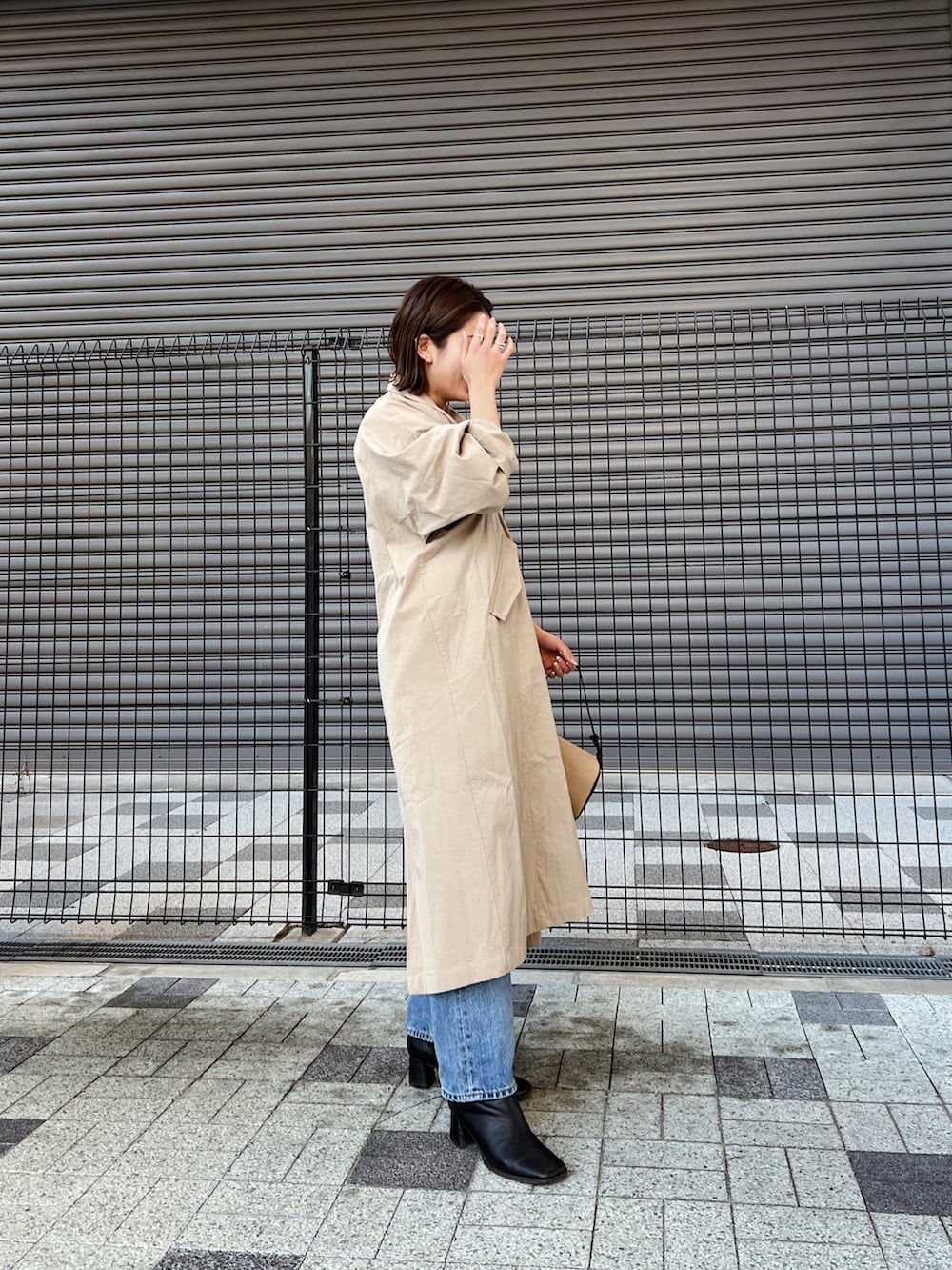 ブルー系のデニムパンツ、ベージュ系のステンカラーコート、グレー系のニット/セーターを着用したレディースの冬コーディネートの4枚目の写真