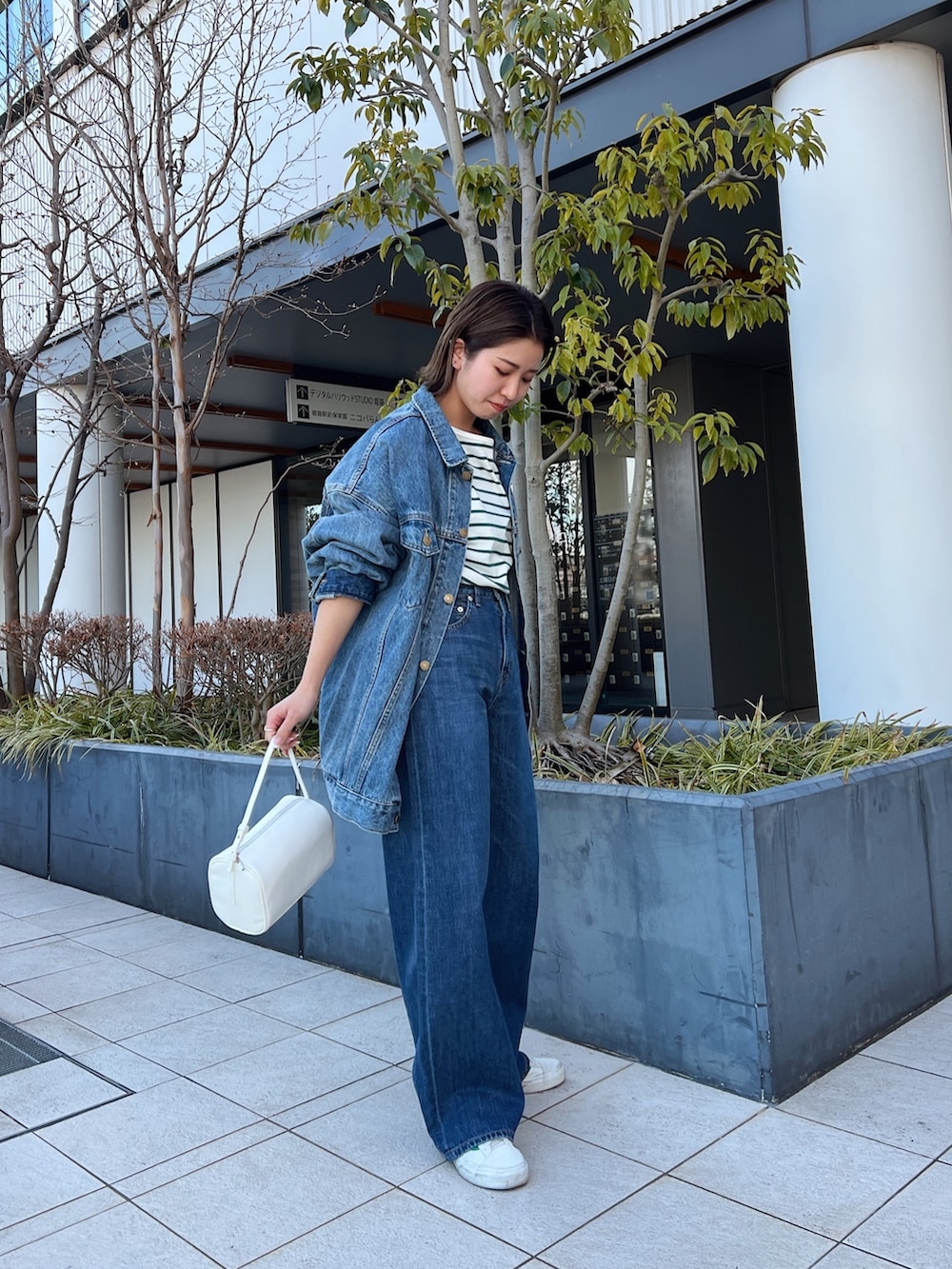 ブルー系のデニムパンツ、ホワイト系のハンドバッグ、ブルー系のデニムジャケットを着用したレディースの冬コーディネートの5枚目の写真