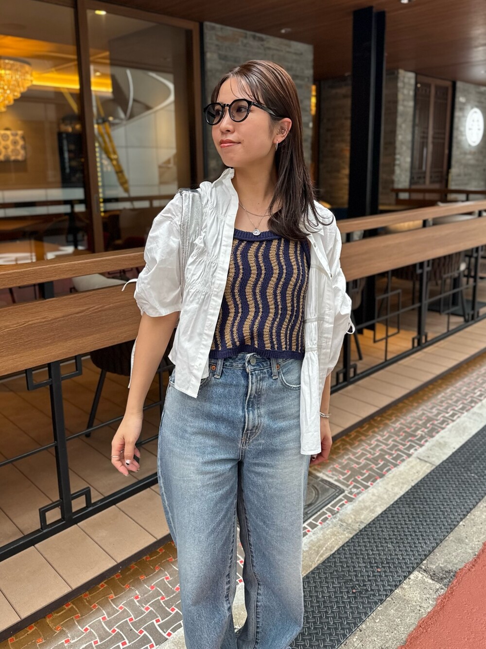 ブルー系のデニムパンツ、ホワイト系のシャツ/ブラウス、シルバー系のハンドバッグを着用したレディースの春コーディネートの5枚目の写真