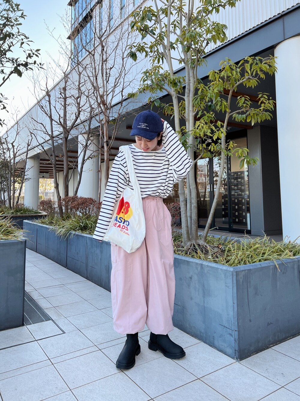 ピンク系のカーゴパンツ、ホワイト系のエコバッグ/サブバッグ、ブルー系のTシャツ/カットソーを着用したレディースの冬コーディネートの5枚目の写真