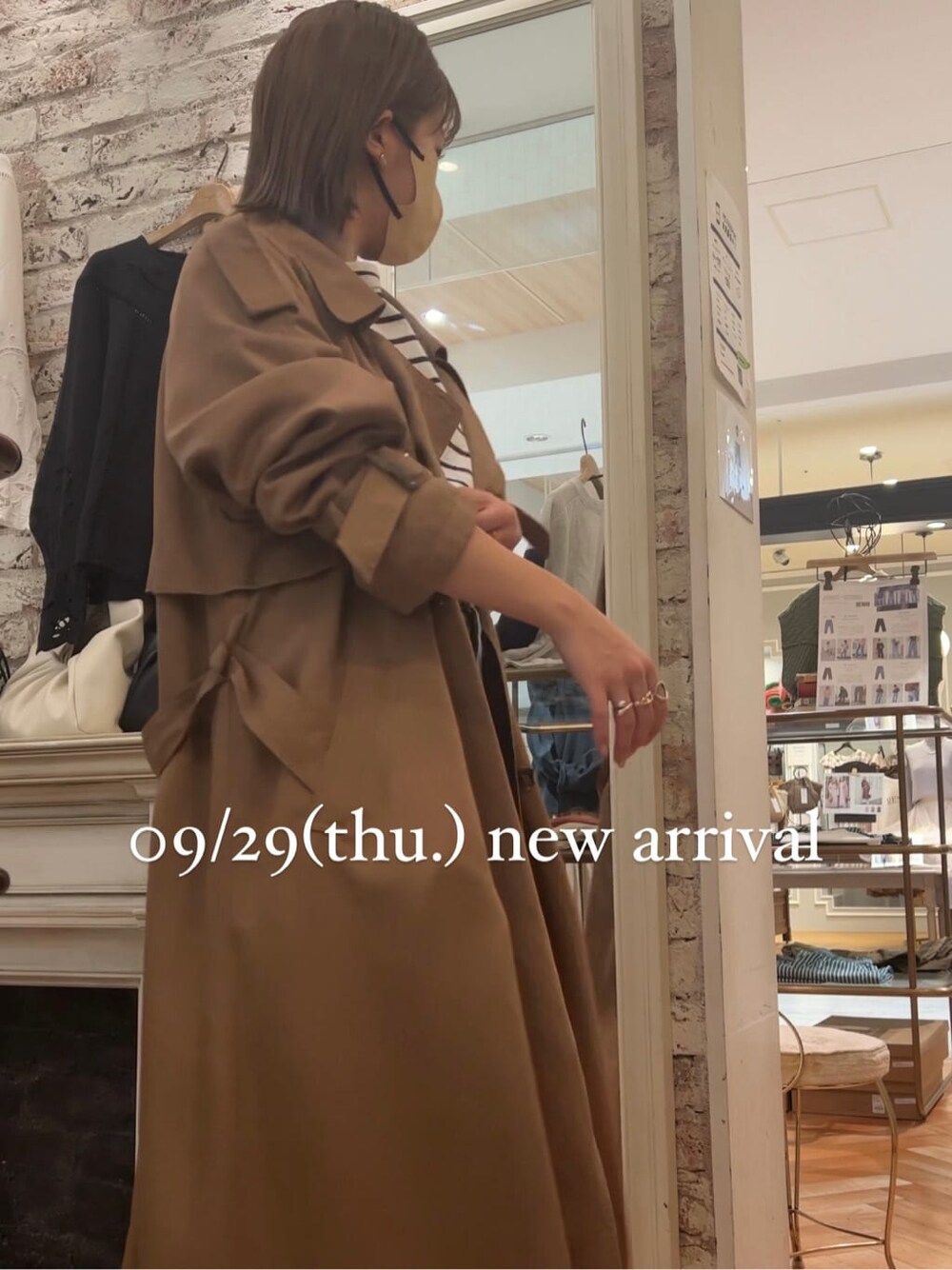 ブルー系のTシャツ/カットソー、イエロー系のトレンチコート、ホワイト系のブーツを着用したレディースの秋コーディネートの3枚目の写真