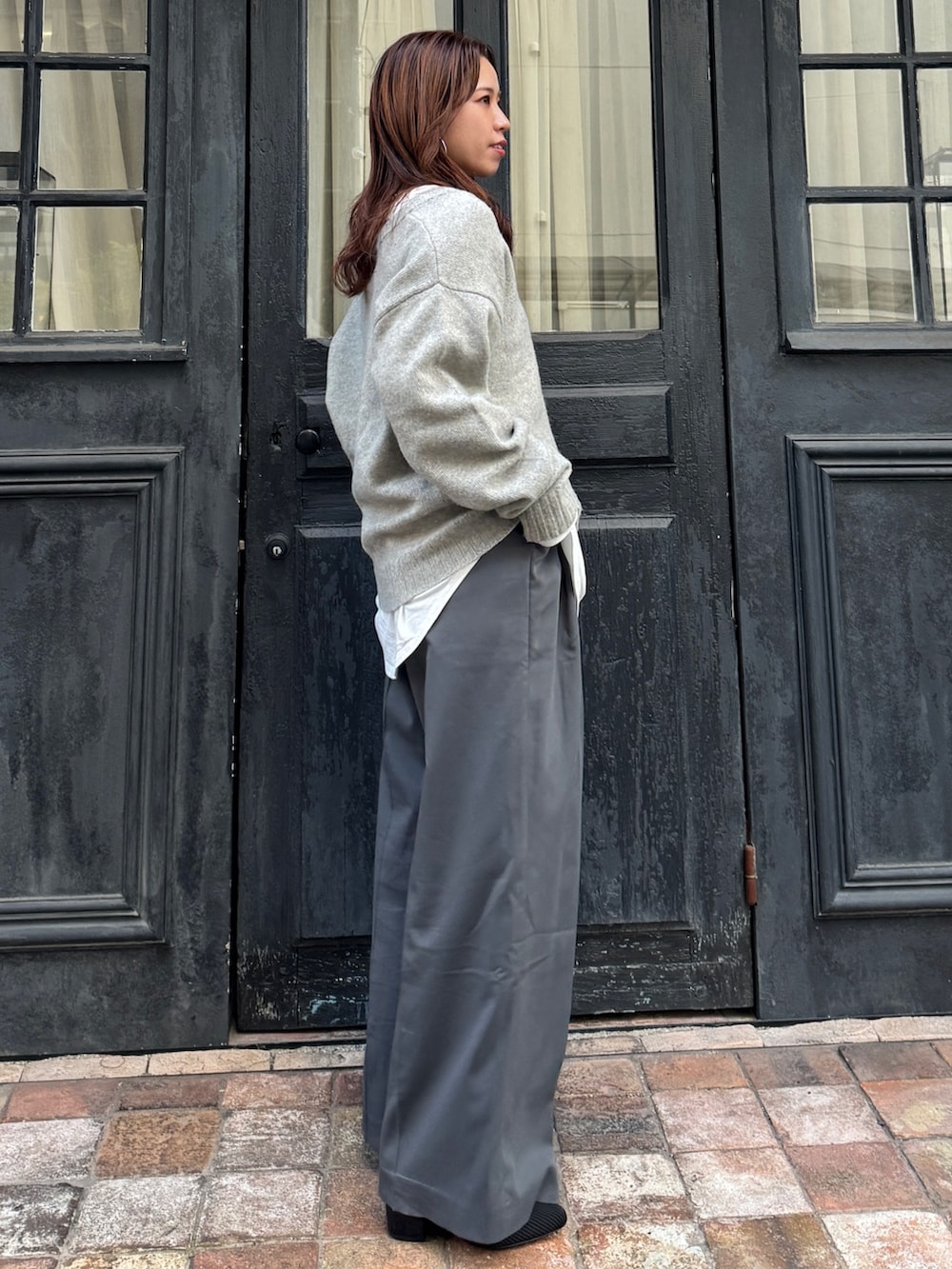 グレー系のニット/セーター、ホワイト系のTシャツ/カットソー、グレー系のその他パンツを着用したレディースの冬コーディネートの2枚目の写真