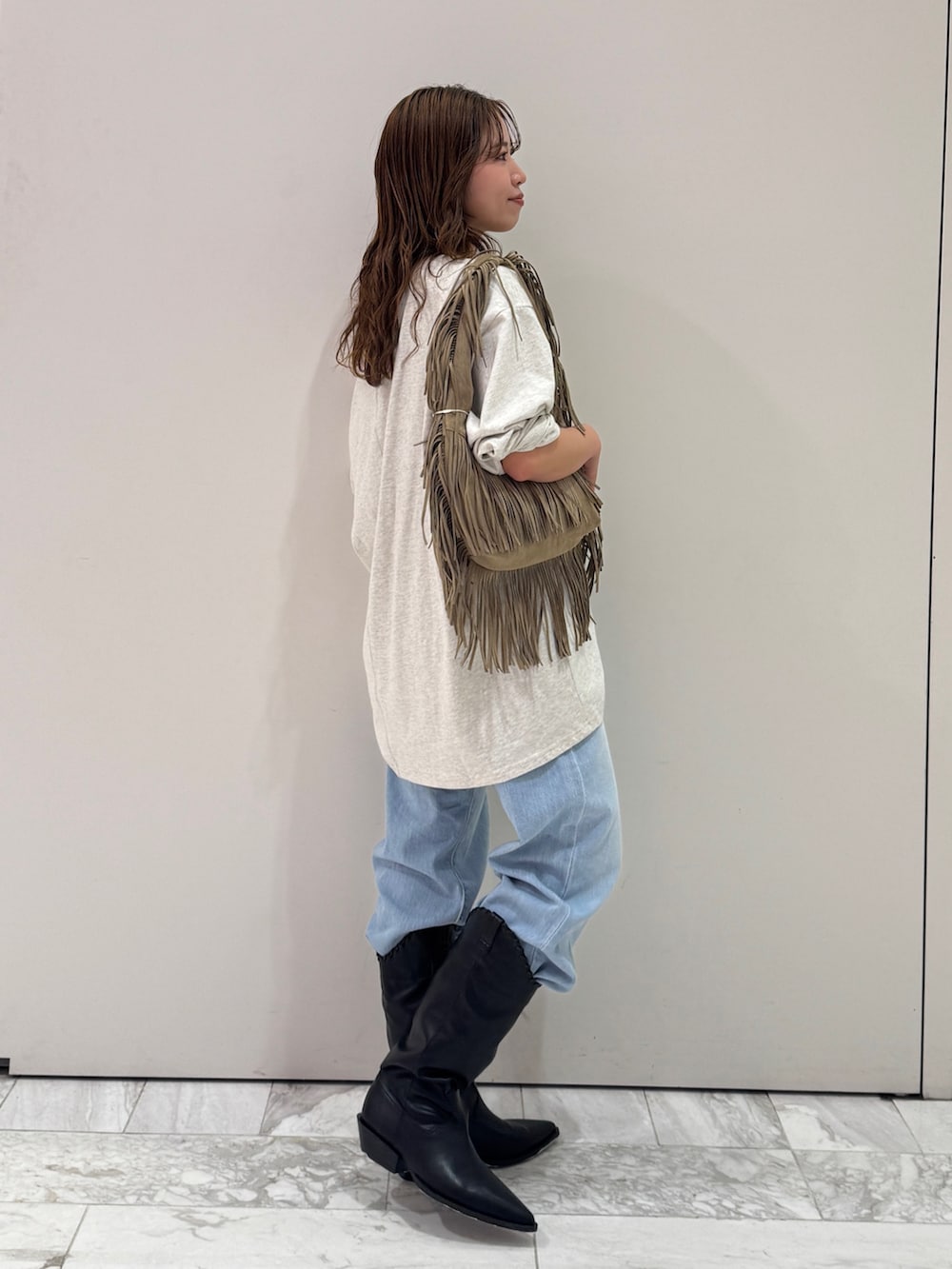 グレー系のTシャツ/カットソー、ベージュ系のハンドバッグ、ブルー系のデニムパンツを着用したレディースの春コーディネートの3枚目の写真