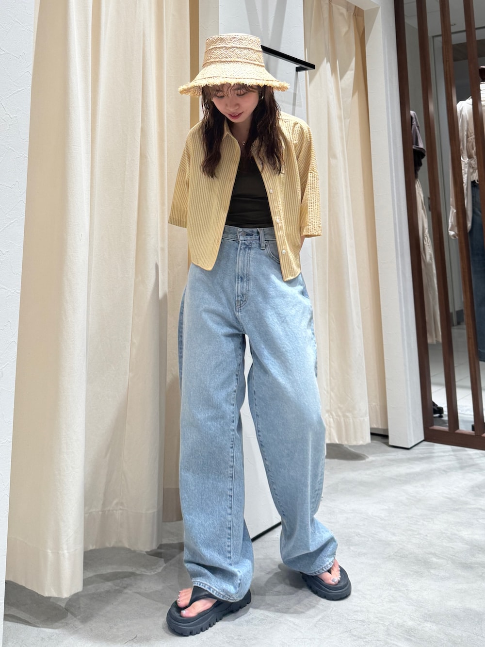 イエロー系のシャツ/ブラウス、ブルー系のデニムパンツ、ベージュ系のハットを着用したレディースの春コーディネートの2枚目の写真