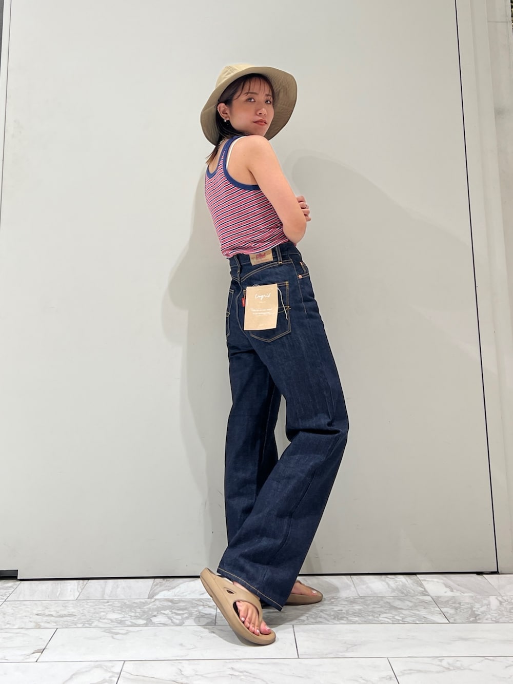 ブルー系のデニムパンツ、ブルー系のタンクトップ、ホワイト系のキャミソールを着用したレディースの夏コーディネートの3枚目の写真