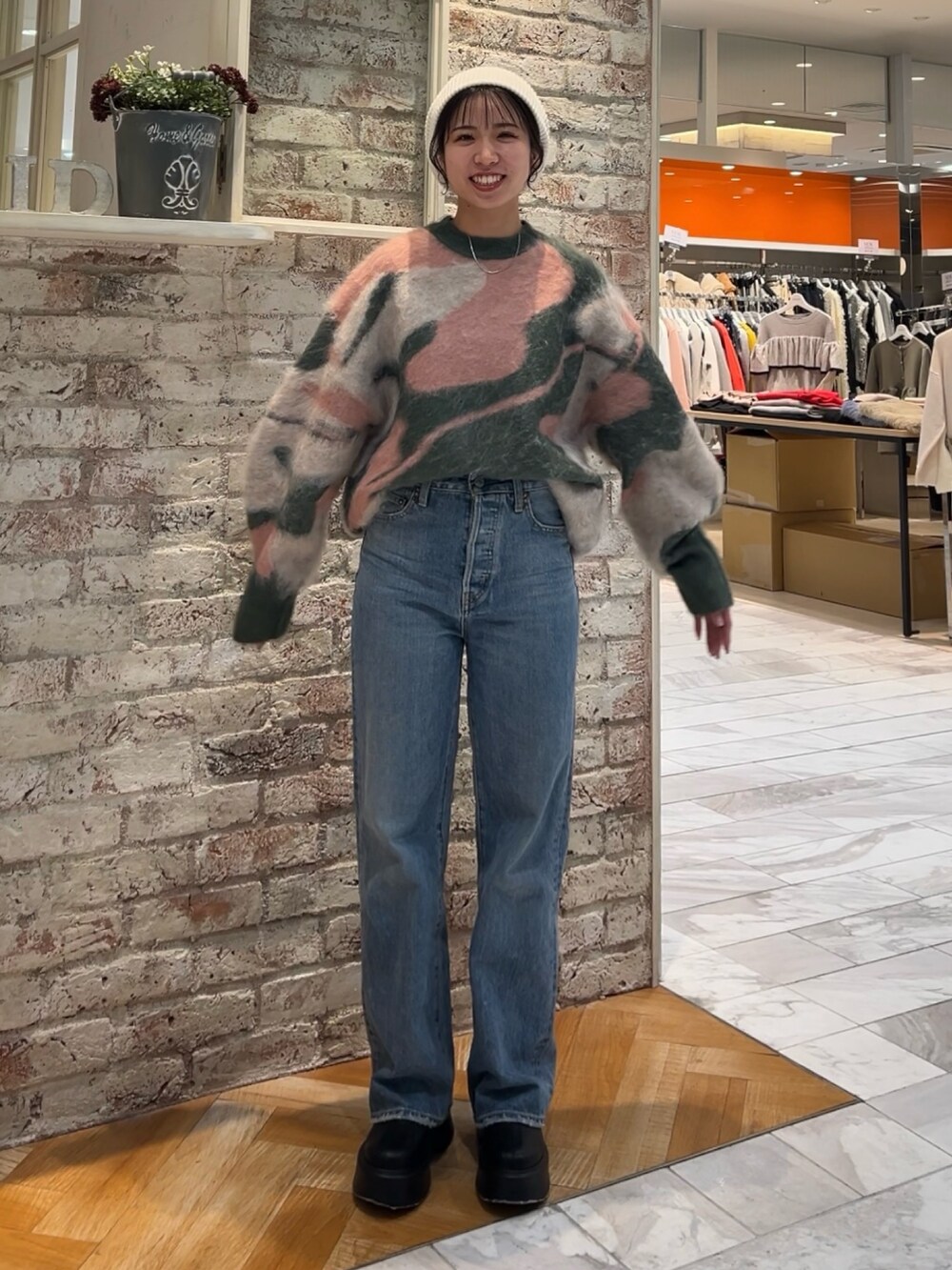 ブラック系のブーツ、グリーン系のニット/セーター、ブルー系のデニムパンツを着用したレディースの秋コーディネートの2枚目の写真