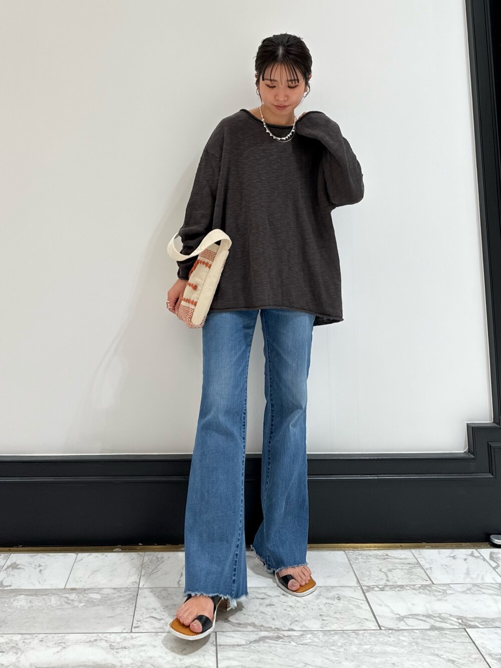 グレー系のニット/セーター、ブルー系のデニムパンツ、ブラック系のサンダルを着用したレディースの春コーディネートの5枚目の写真