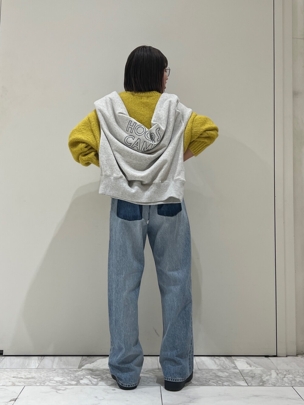 ブルー系のデニムパンツ、イエロー系のニット/セーター、グレー系のスウェットを着用したレディースの冬コーディネートの6枚目の写真