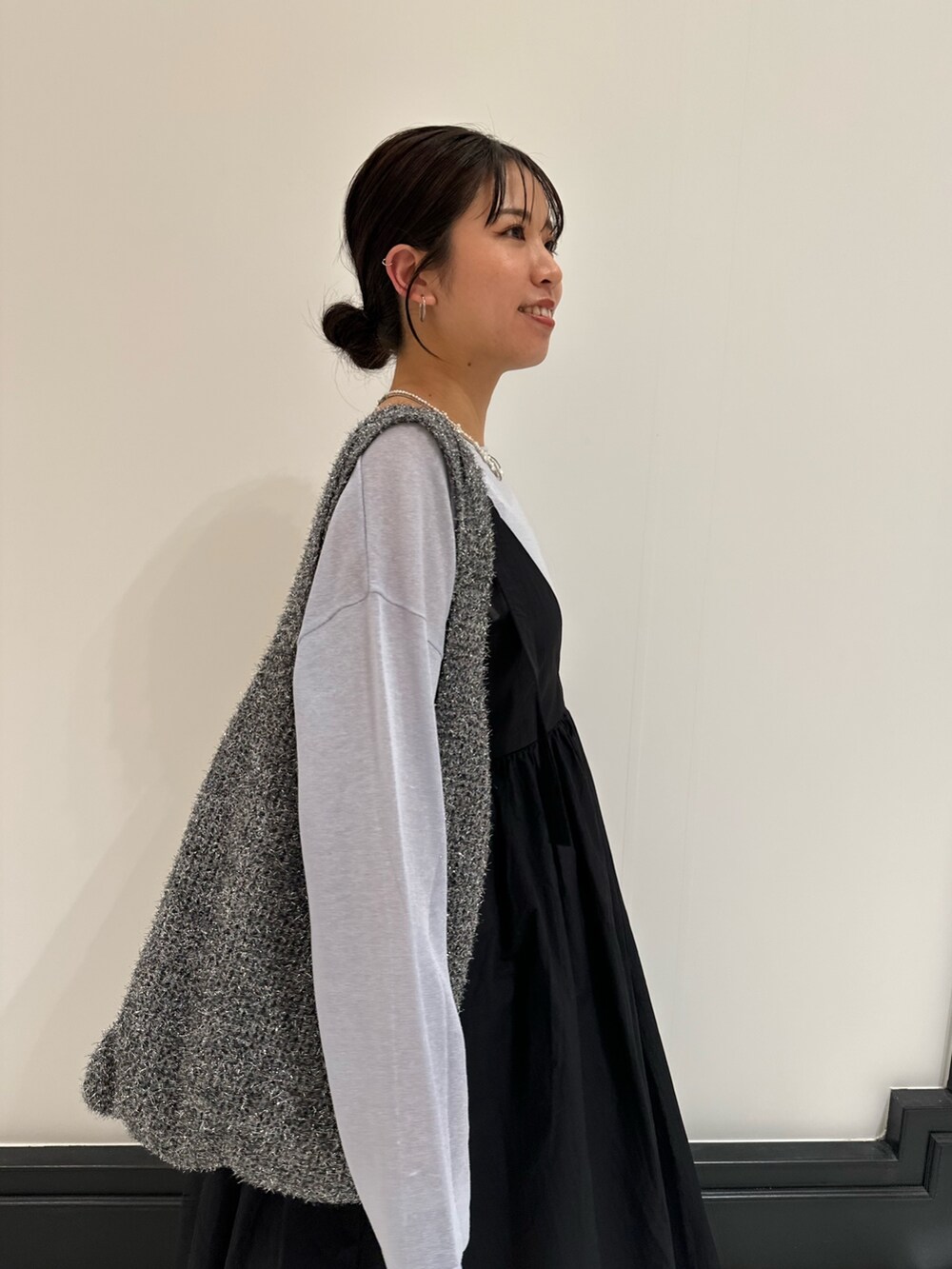 ブラック系のワンピース、ブルー系のニット/セーター、ブルー系のデニムパンツを着用したレディースの春コーディネートの9枚目の写真