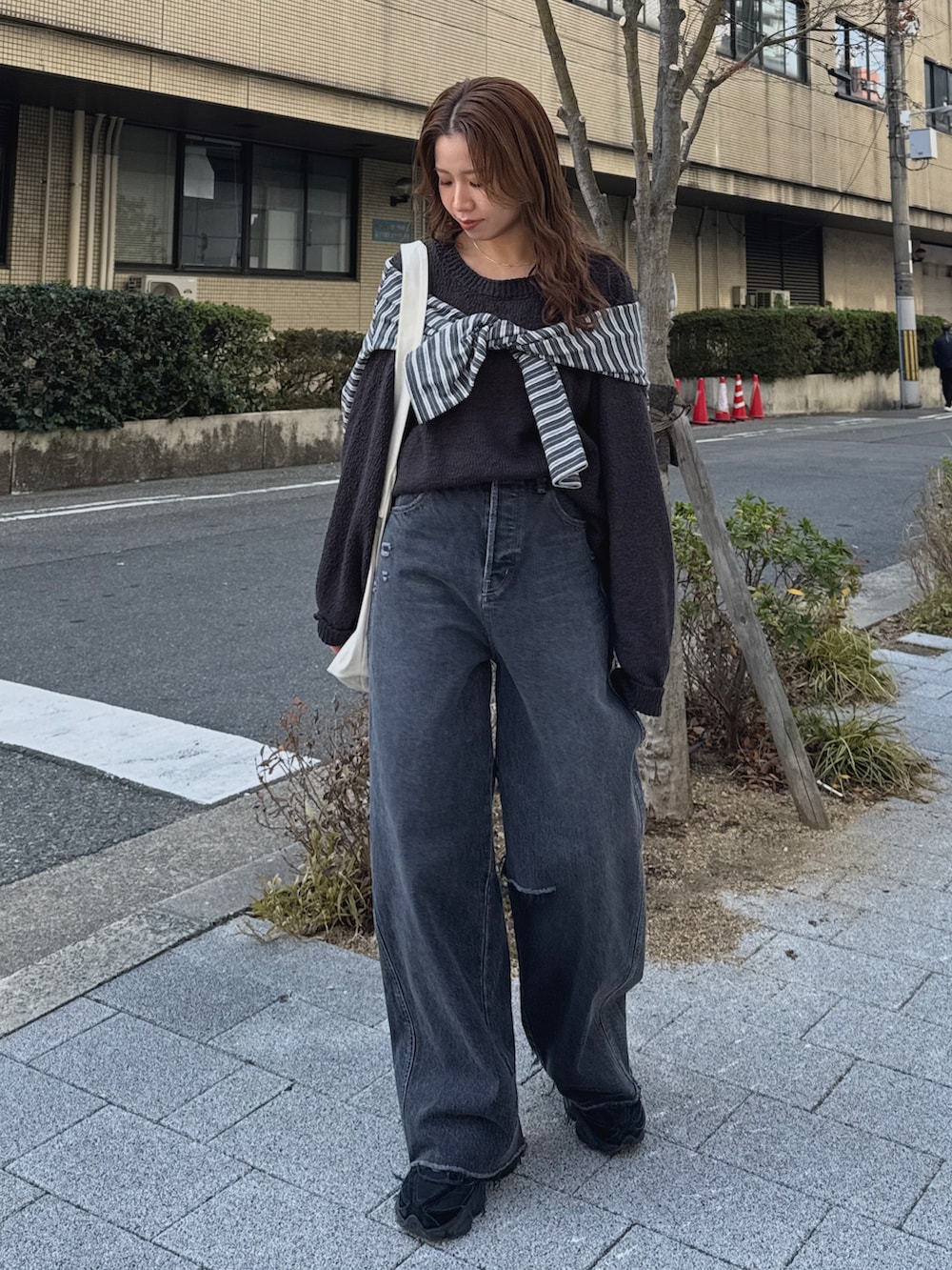 グレー系のニット/セーター、グレー系のTシャツ/カットソー、ブラック系のデニムパンツを着用したレディースの冬コーディネートの6枚目の写真