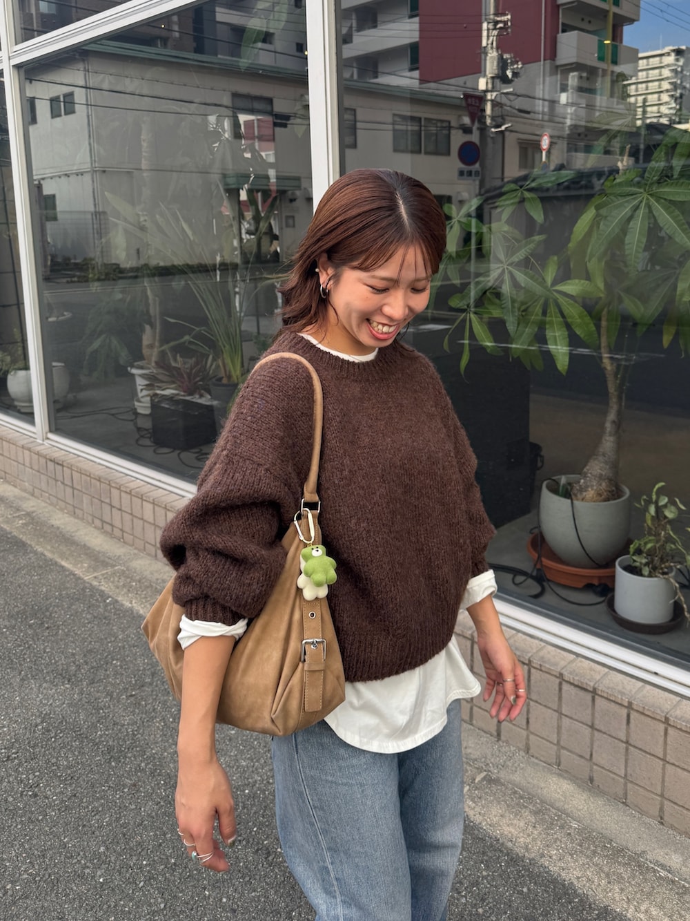 ホワイト系のTシャツ/カットソー、ブラウン系のニット/セーター、ブルー系のデニムパンツを着用したレディースの秋コーディネートの7枚目の写真