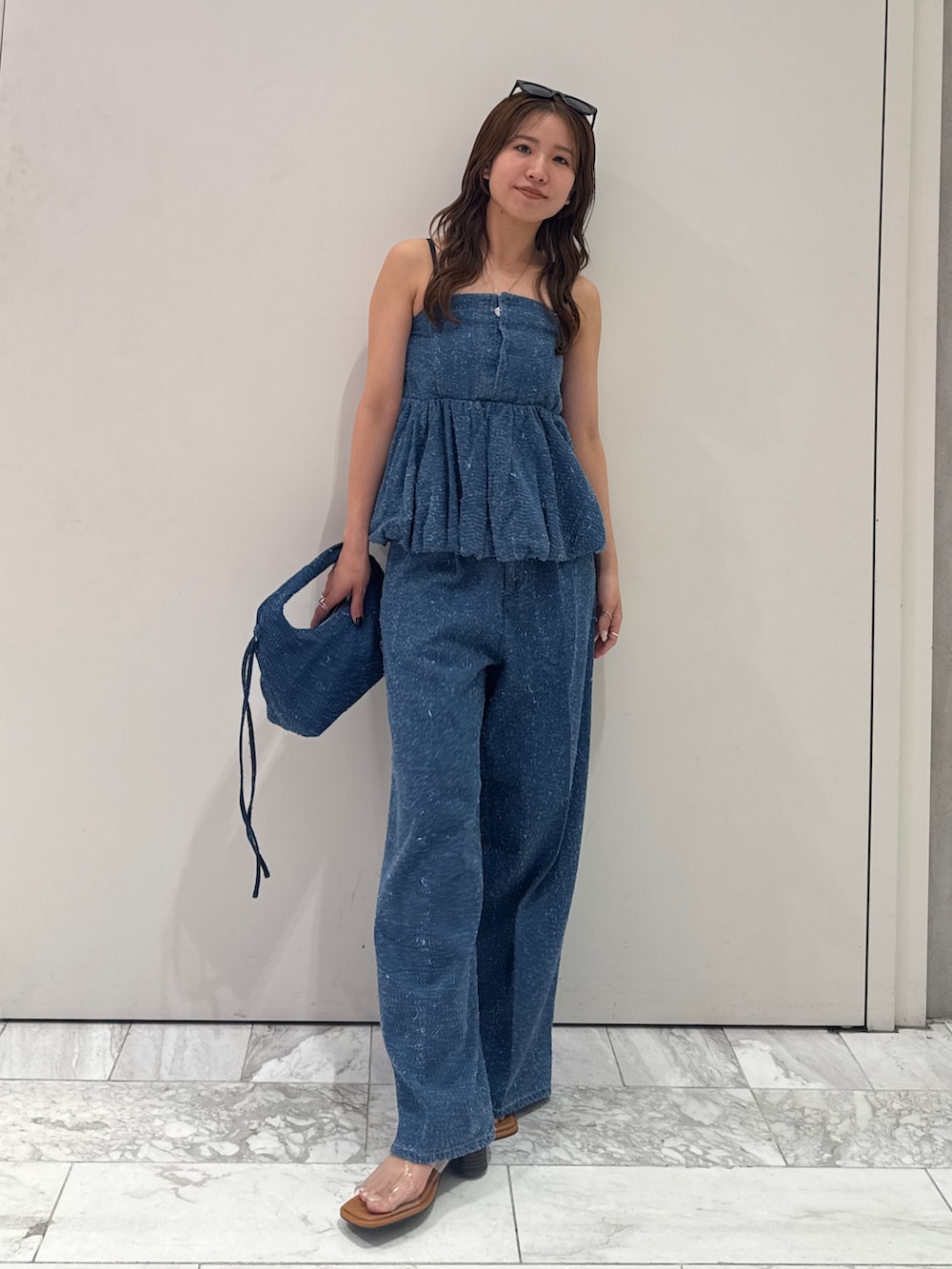 ブルー系のチューブトップ、ブルー系のデニムパンツ、ブルー系のハンドバッグを着用したレディースの春コーディネートの7枚目の写真