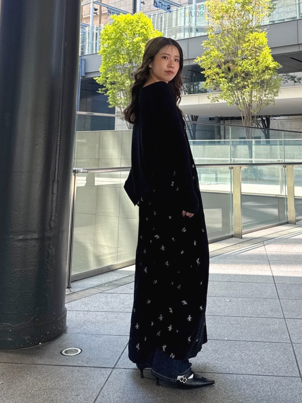 ブルー系のデニムパンツ、ブラック系のパンプス、ブラック系のワンピースを着用したレディースの秋コーディネートの4枚目の写真