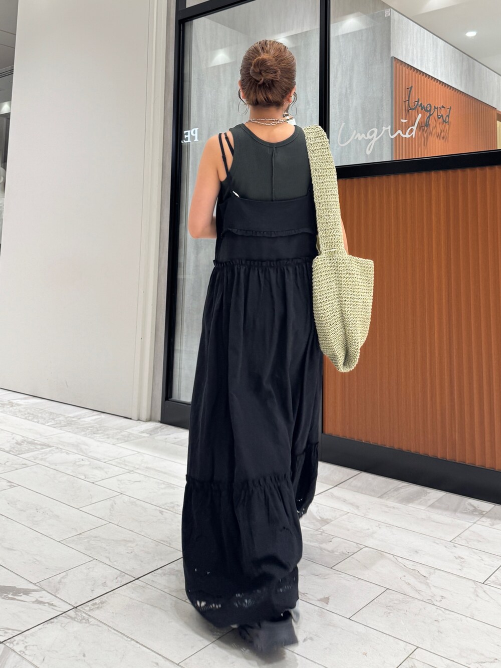 ブラック系のワンピース、グレー系のタンクトップ、ブルー系のデニムパンツを着用したレディースの春コーディネートの4枚目の写真