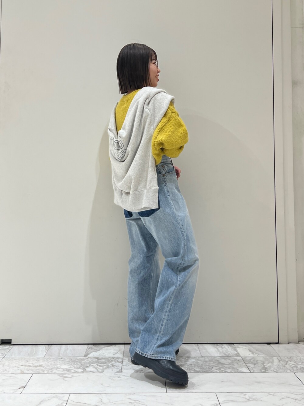 ブルー系のデニムパンツ、イエロー系のニット/セーター、グレー系のスウェットを着用したレディースの冬コーディネートの4枚目の写真