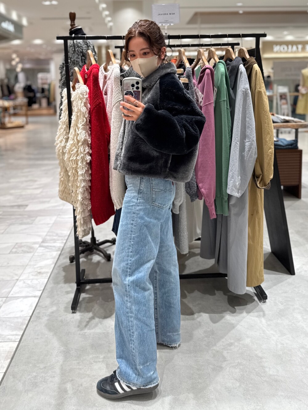 グレー系のブルゾン、グレー系のニット/セーター、ブルー系のデニムパンツを着用したレディースの秋コーディネートの4枚目の写真