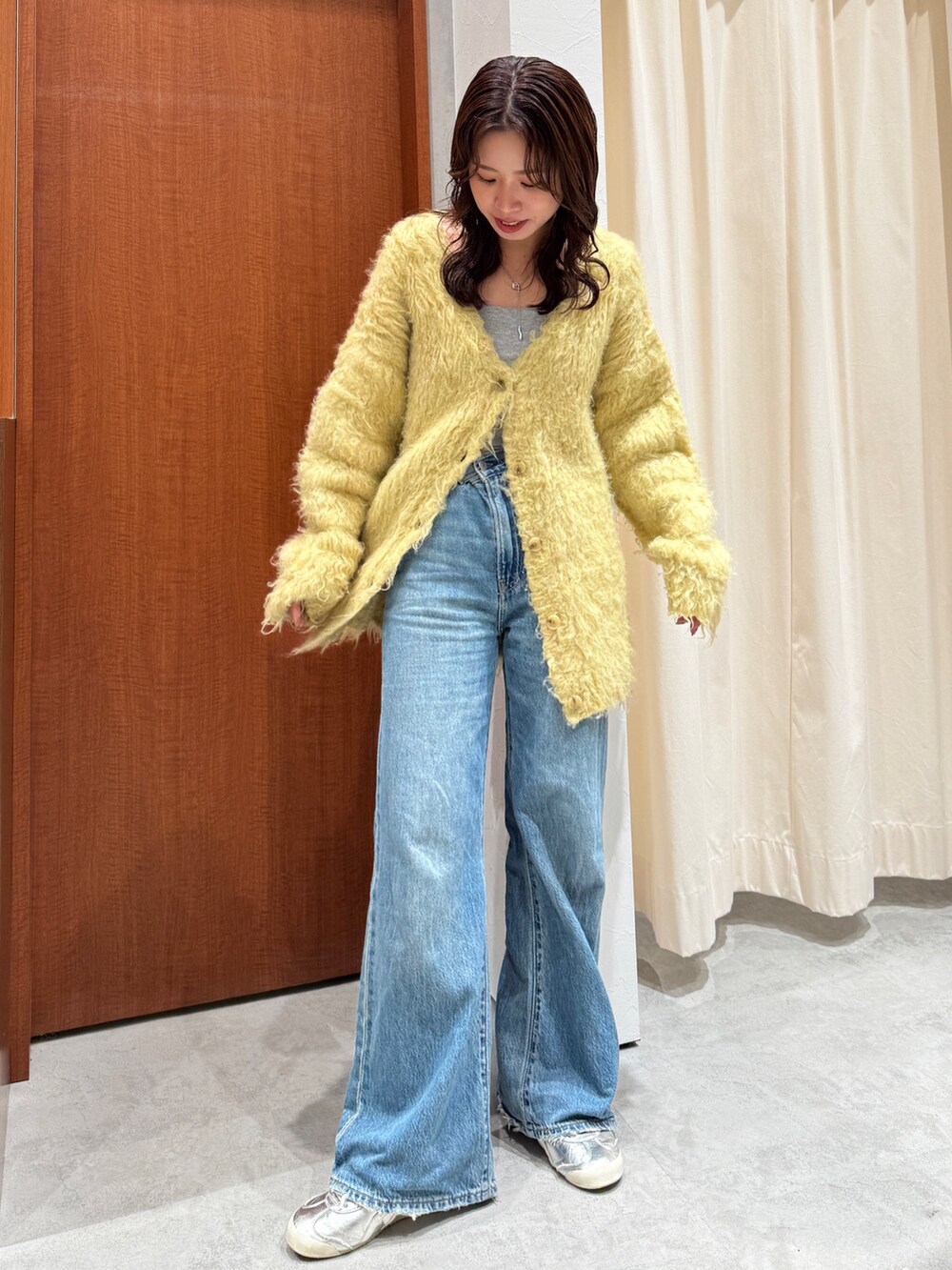 ブルー系のデニムパンツ、イエロー系のカーディガン/ボレロを着用したレディースの秋コーディネートの2枚目の写真