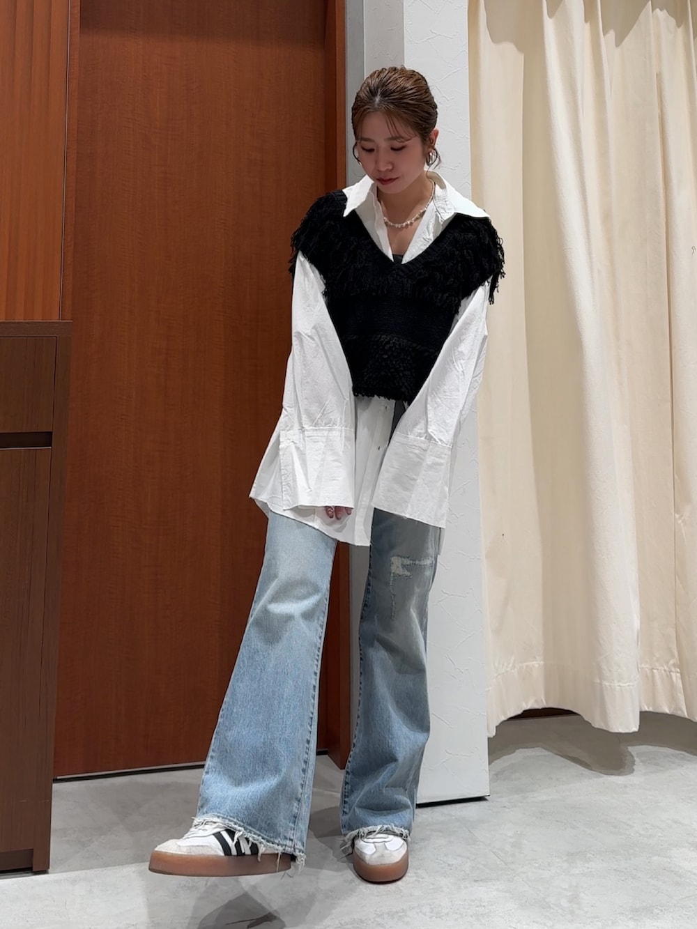 ブラック系のベスト、ホワイト系のシャツ/ブラウス、ブルー系のデニムパンツを着用したレディースの春コーディネートの3枚目の写真