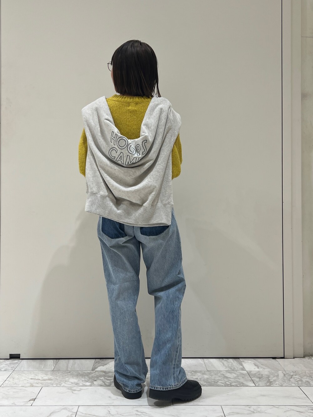 ブルー系のデニムパンツ、イエロー系のニット/セーター、グレー系のスウェットを着用したレディースの冬コーディネートの5枚目の写真