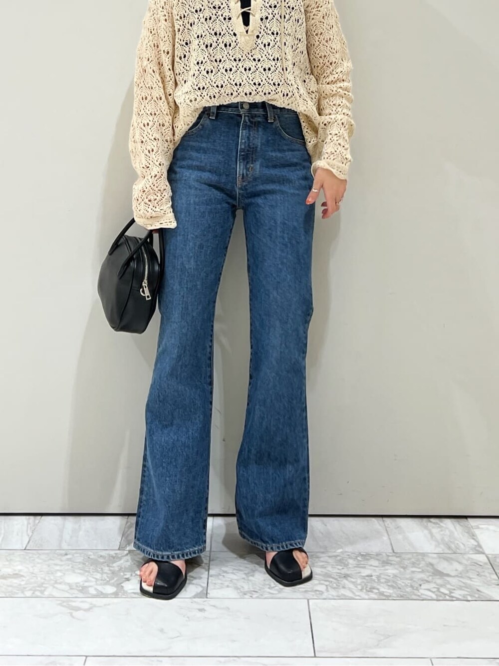 ブラック系のサンダル、ブラック系のハンドバッグ、ブルー系のデニムパンツを着用したレディースの春コーディネートの5枚目の写真