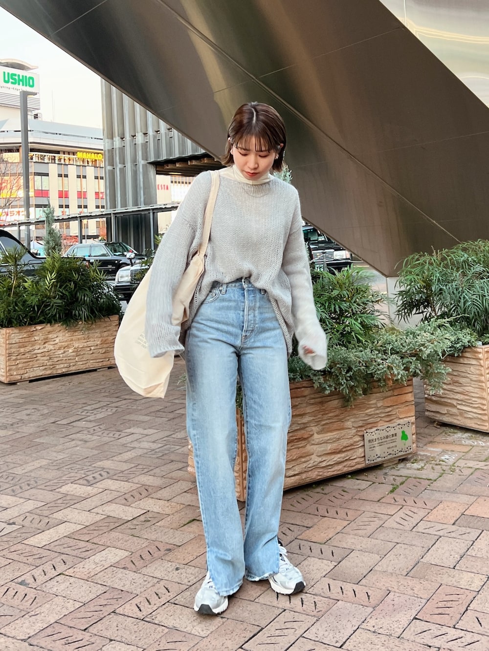 ベージュ系のムートンコート、ホワイト系のハンドバッグ、グレー系のニット/セーターを着用したレディースの冬コーディネートの8枚目の写真