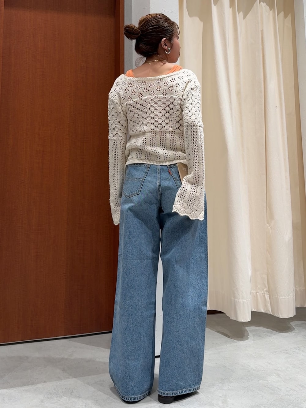 ブルー系のデニムパンツ、オレンジ系のタンクトップ、ホワイト系のカーディガン/ボレロを着用したレディースの春コーディネートの5枚目の写真