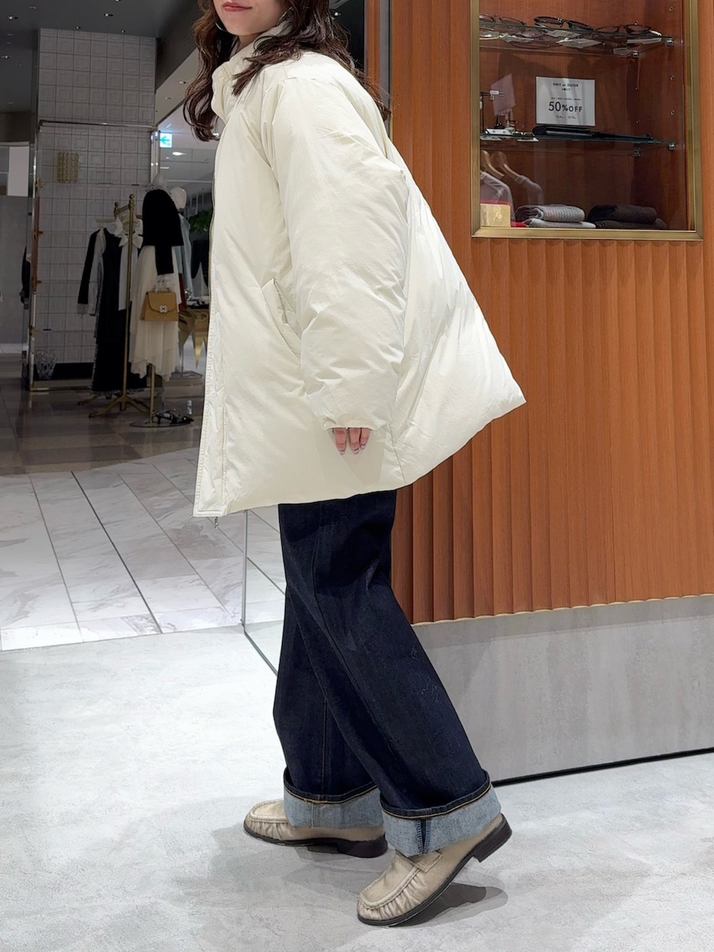 ホワイト系のダウンジャケット/コート、グレー系のニット/セーター、ブルー系のデニムパンツを着用したレディースの冬コーディネートの5枚目の写真