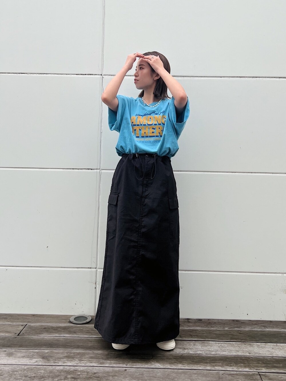ブルー系のTシャツ/カットソー、ブラック系のスカート、ホワイト系のスニーカーを着用したレディースの春コーディネートの3枚目の写真