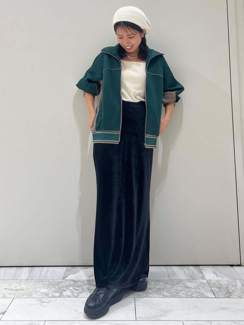 ブラック系のスカート、グリーン系のブルゾン、ホワイト系のキャミソールを着用したレディースの秋コーディネートの7枚目の写真