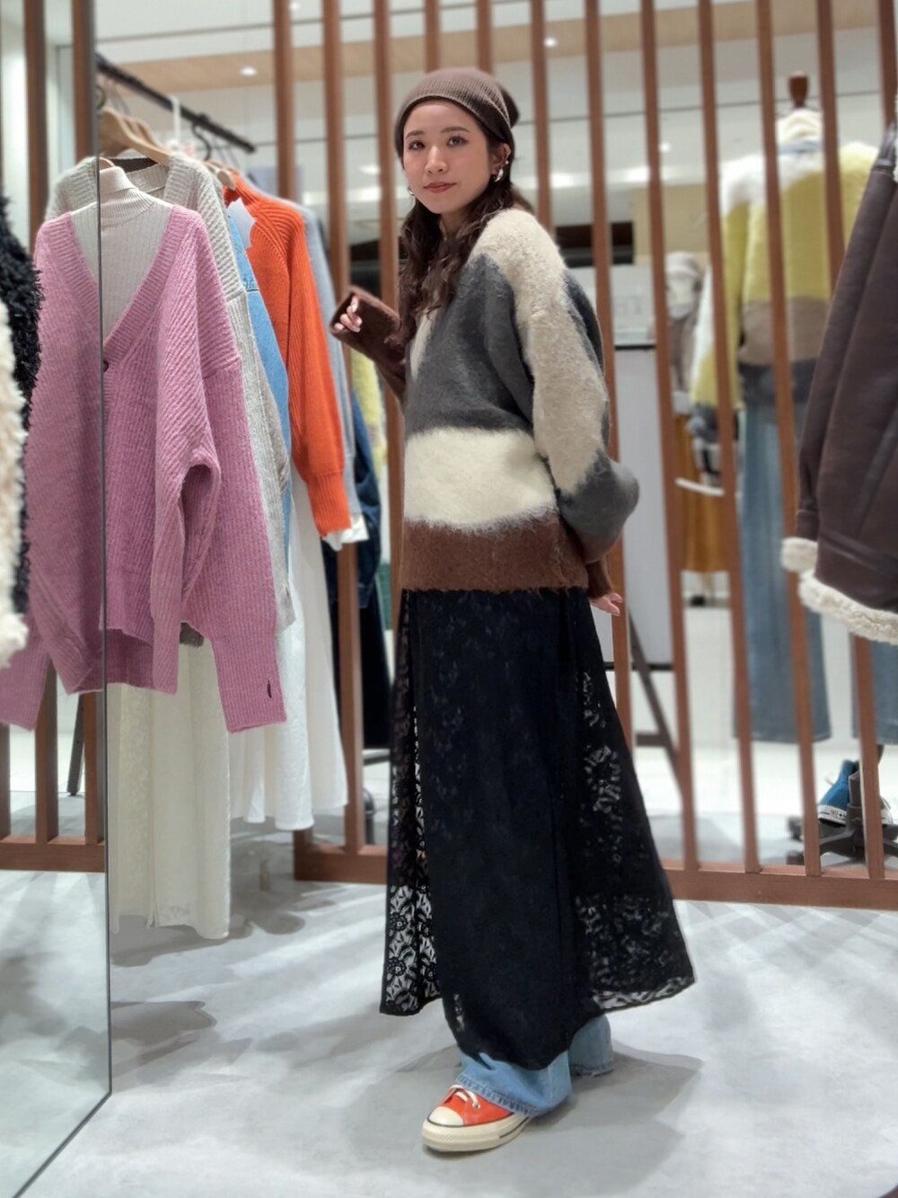 グレー系のニット/セーター、ブラック系のワンピース、ブルー系のデニムパンツを着用したレディースの秋コーディネートの4枚目の写真