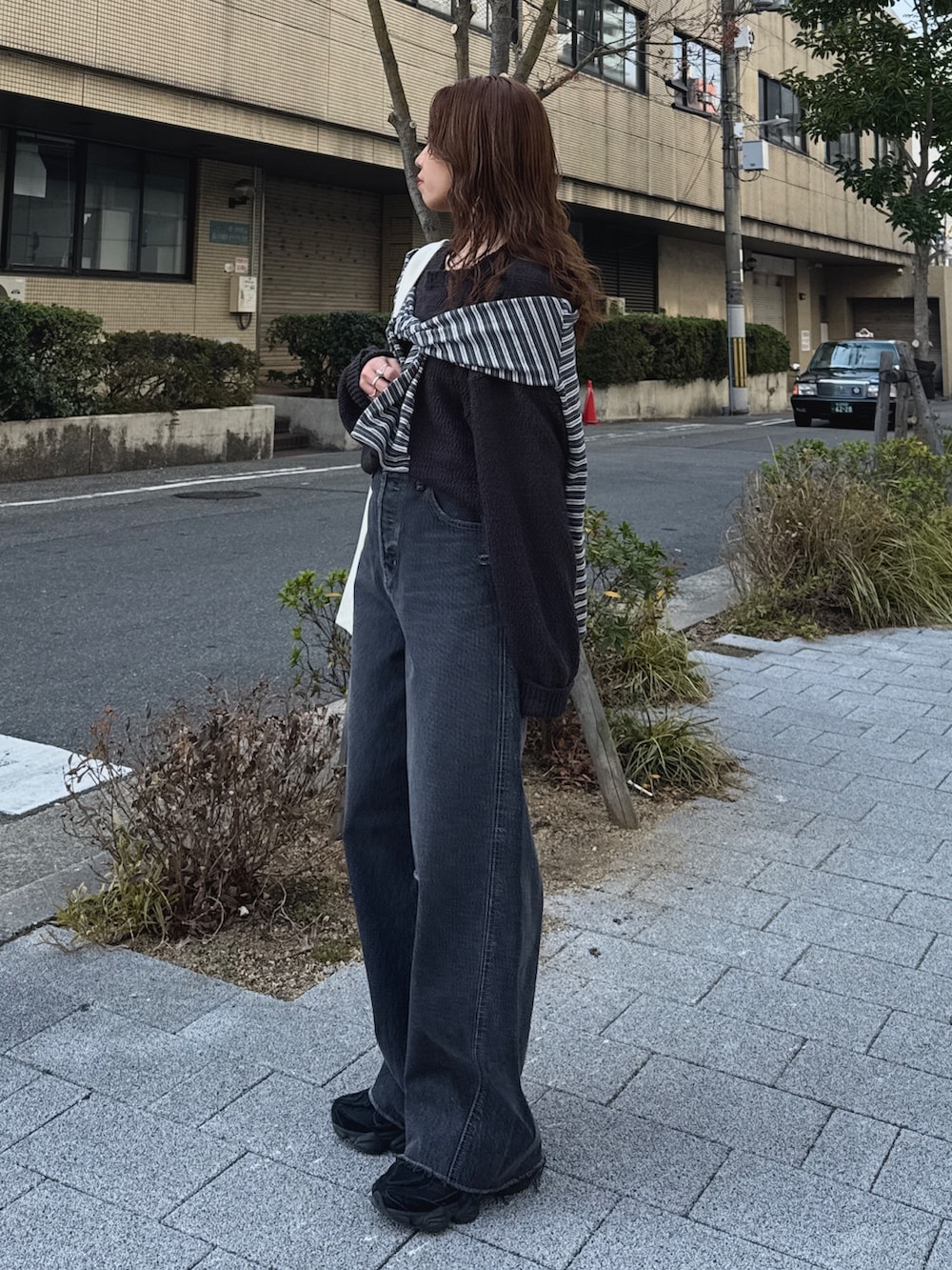 グレー系のニット/セーター、グレー系のTシャツ/カットソー、ブラック系のデニムパンツを着用したレディースの冬コーディネートの5枚目の写真