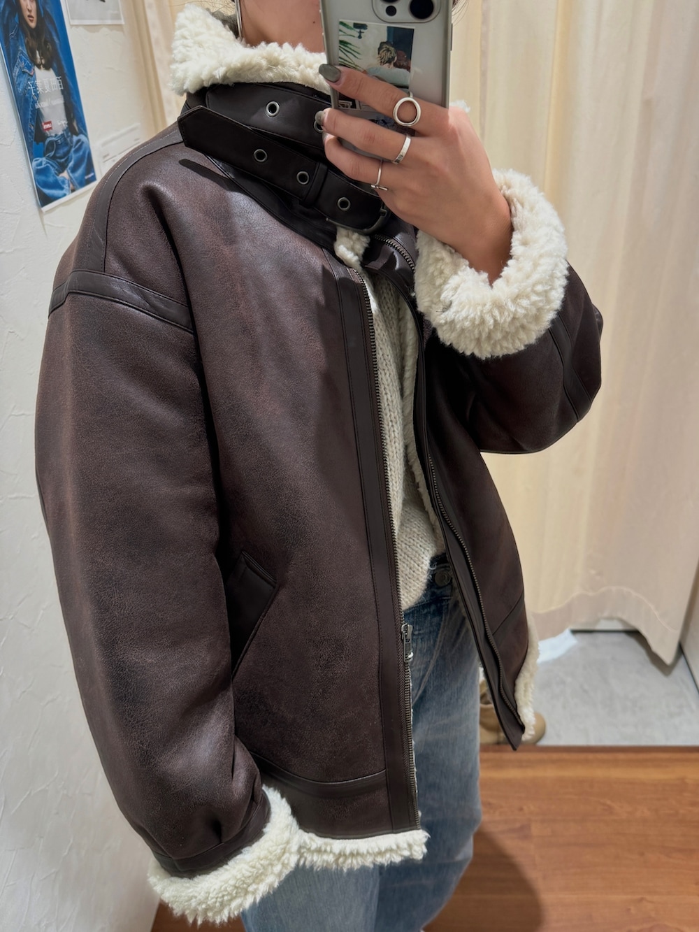 ブルー系のデニムパンツ、ブラウン系のブルゾン、ホワイト系のニット/セーターを着用したレディースの秋コーディネートの2枚目の写真