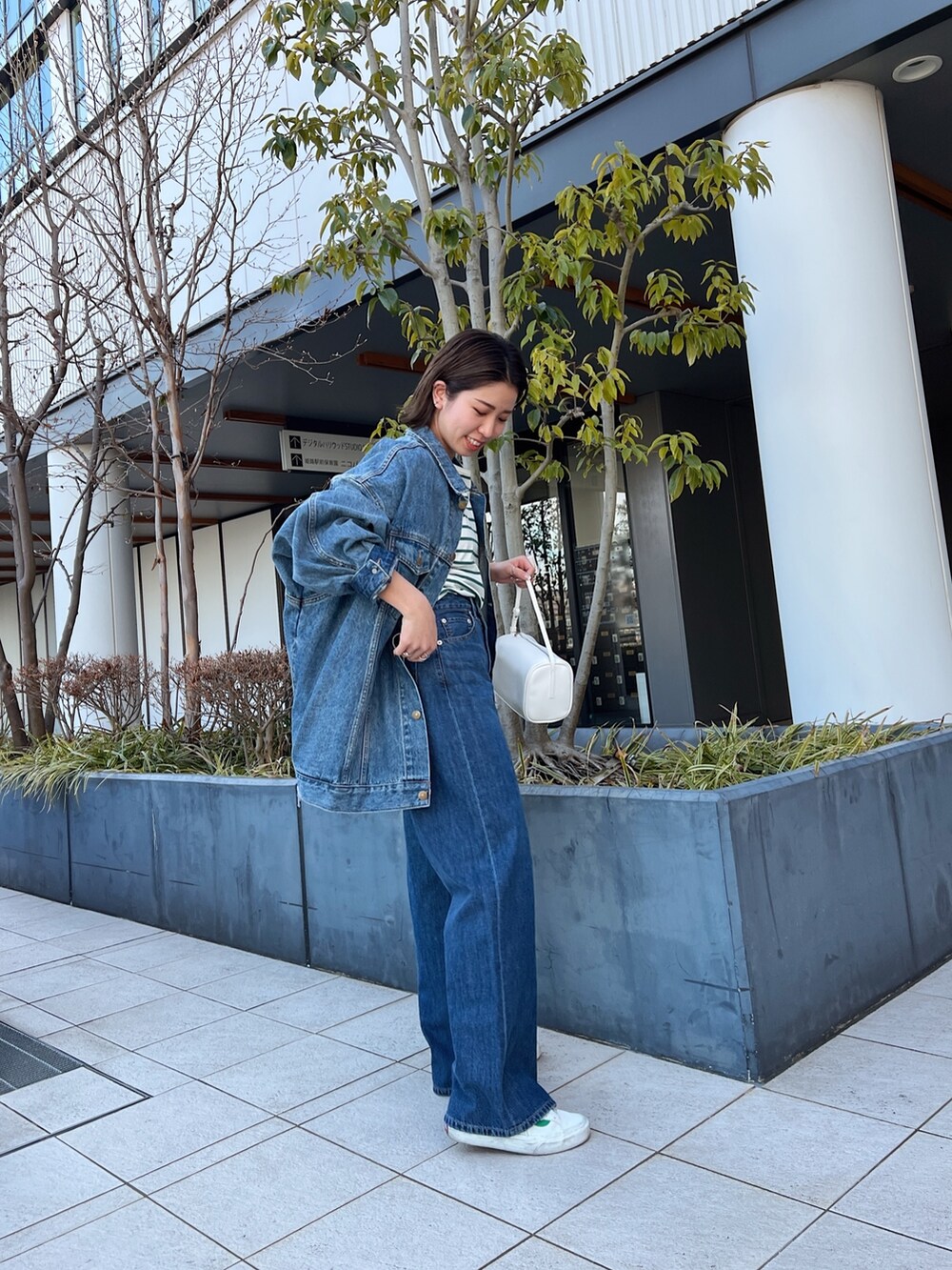 ブルー系のデニムパンツ、ホワイト系のハンドバッグ、ブルー系のデニムジャケットを着用したレディースの冬コーディネートの4枚目の写真