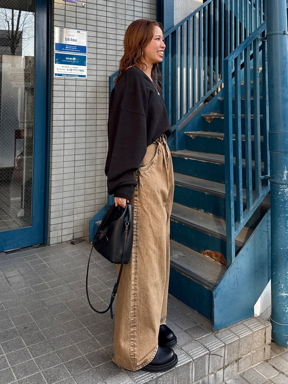 ブラウン系のデニムパンツ、ブラック系のスウェットを着用したレディースの冬コーディネートの4枚目の写真