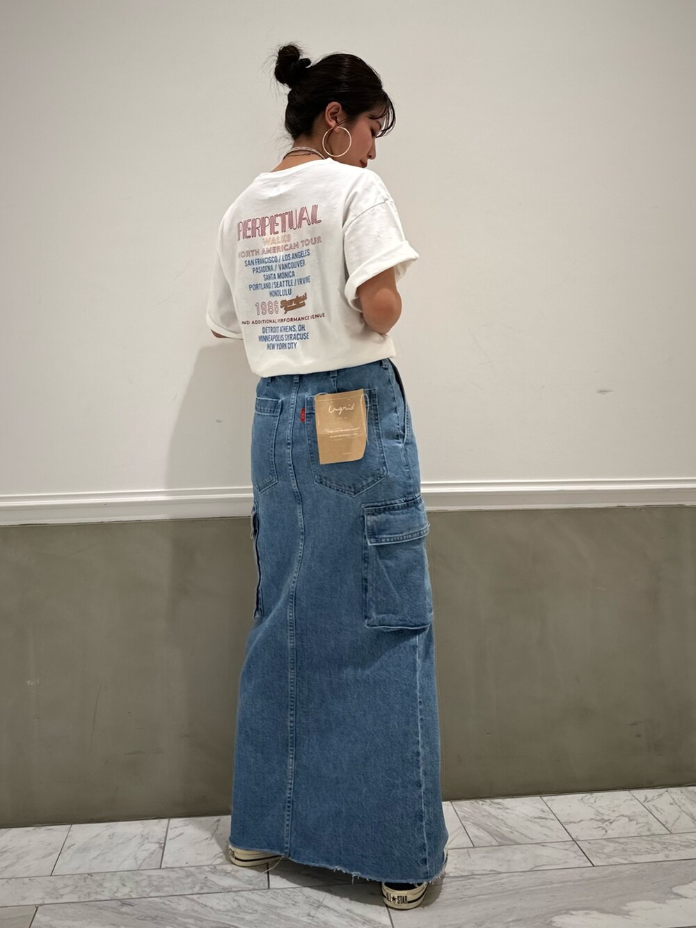 ブルー系のデニムスカート、ホワイト系のTシャツ/カットソー、ブルー系のスニーカーを着用したレディースの春コーディネートの3枚目の写真