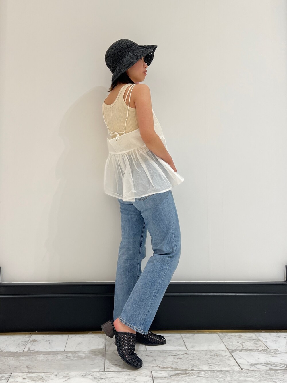 ホワイト系のシャツ/ブラウス、ベージュ系のタンクトップ、ブルー系のデニムパンツを着用したレディースの春コーディネートの4枚目の写真