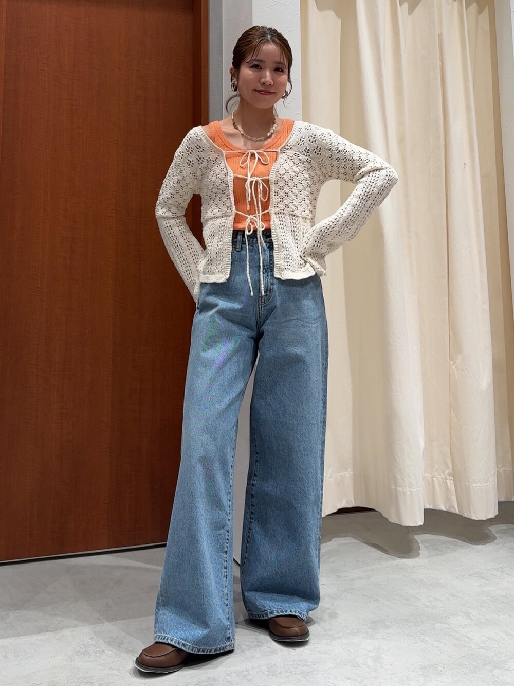 ブルー系のデニムパンツ、オレンジ系のタンクトップ、ホワイト系のカーディガン/ボレロを着用したレディースの春コーディネートの2枚目の写真