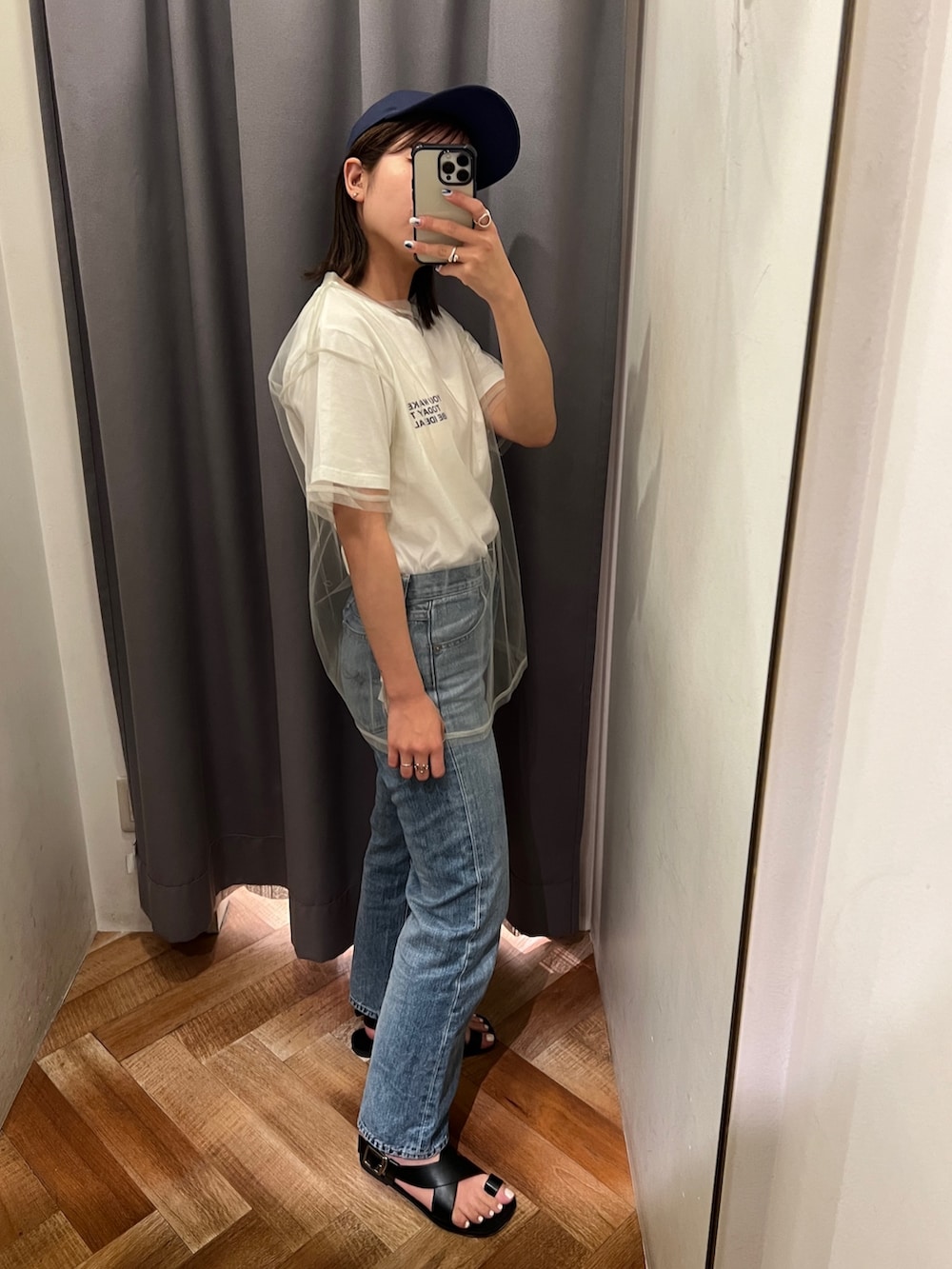 ブルー系のデニムパンツ、ブラック系のサンダル、ホワイト系のTシャツ/カットソーを着用したレディースの春コーディネートの2枚目の写真