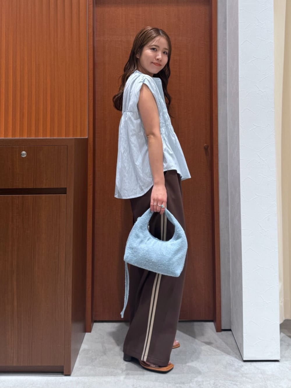 その他のサンダル、ブラウン系のその他パンツ、ブルー系のハンドバッグを着用したレディースの夏コーディネートの3枚目の写真