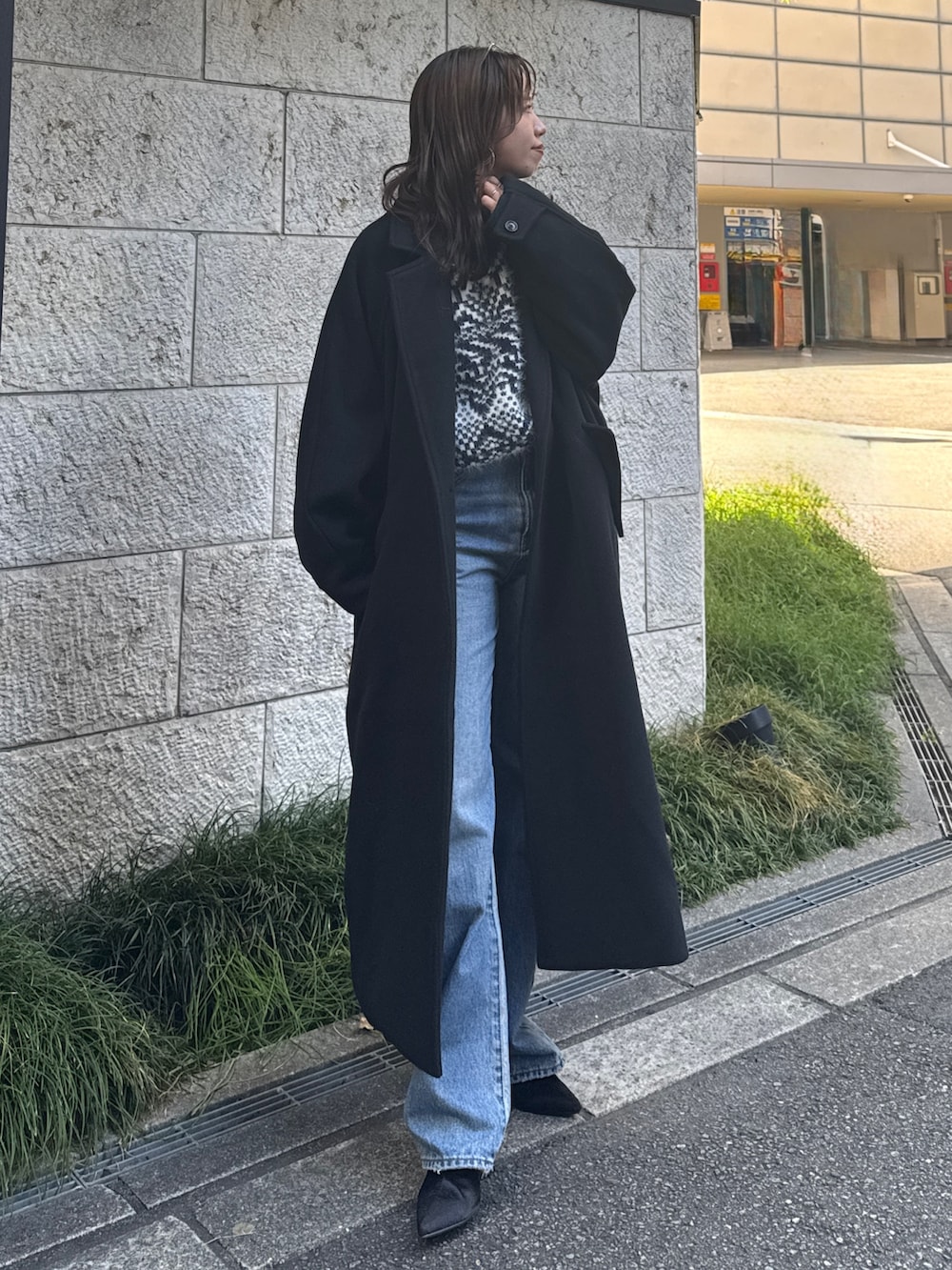 ブルー系のデニムパンツ、ブルー系のニット/セーター、ブラック系のチェスターコートを着用したレディースの秋コーディネートの2枚目の写真