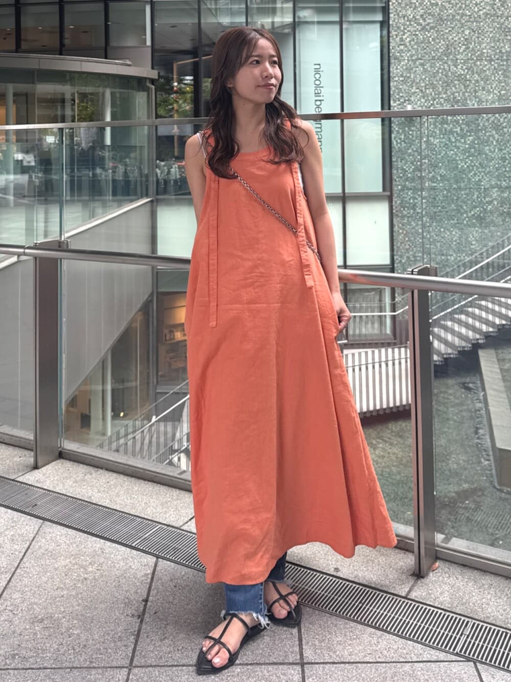 ブルー系のデニムパンツ、オレンジ系のワンピースを着用したレディースの春コーディネートの6枚目の写真