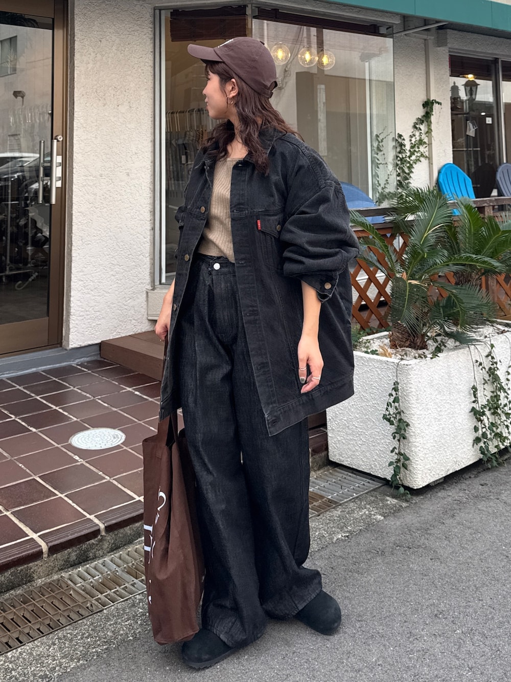 ブラック系のデニムジャケット、ブラック系のデニムパンツ、ブラウン系のトートバッグを着用したレディースの秋コーディネートの3枚目の写真