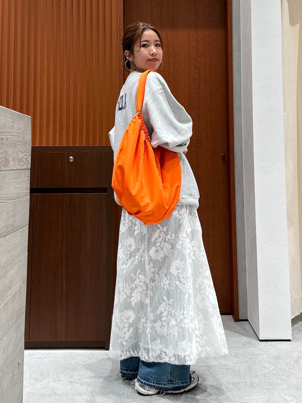 ホワイト系のワンピース、グレー系のスウェット、ブルー系のデニムパンツを着用したレディースの秋コーディネートの5枚目の写真