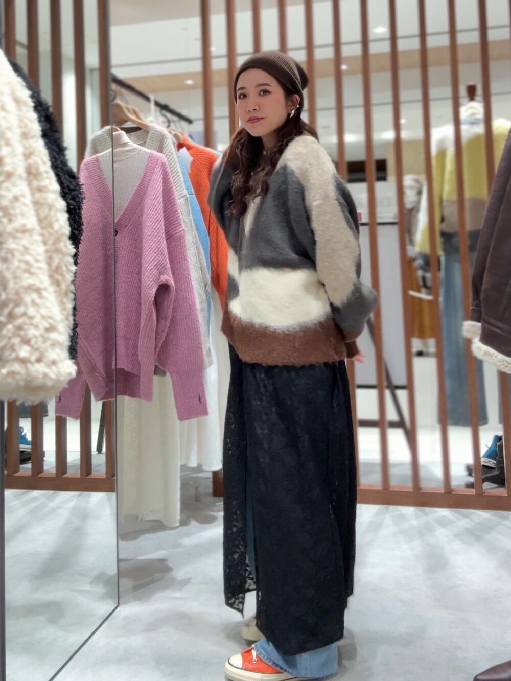 グレー系のニット/セーター、ブラック系のワンピース、ブルー系のデニムパンツを着用したレディースの秋コーディネートの3枚目の写真