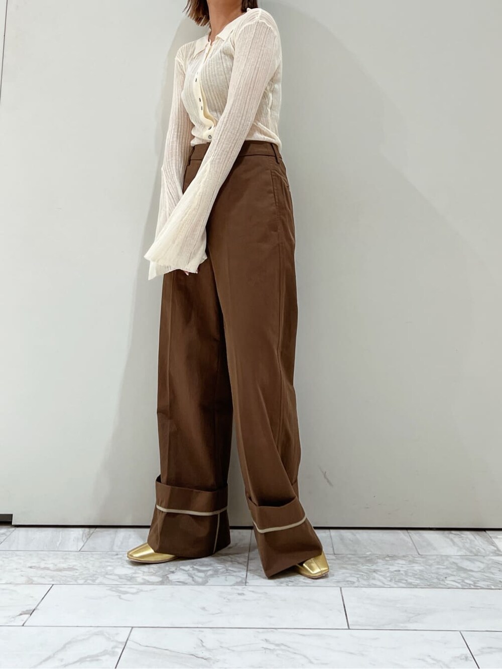 ブラウン系のチノパンツ、ゴールド系のパンプス、ホワイト系のカーディガン/ボレロを着用したレディースの夏コーディネートの2枚目の写真
