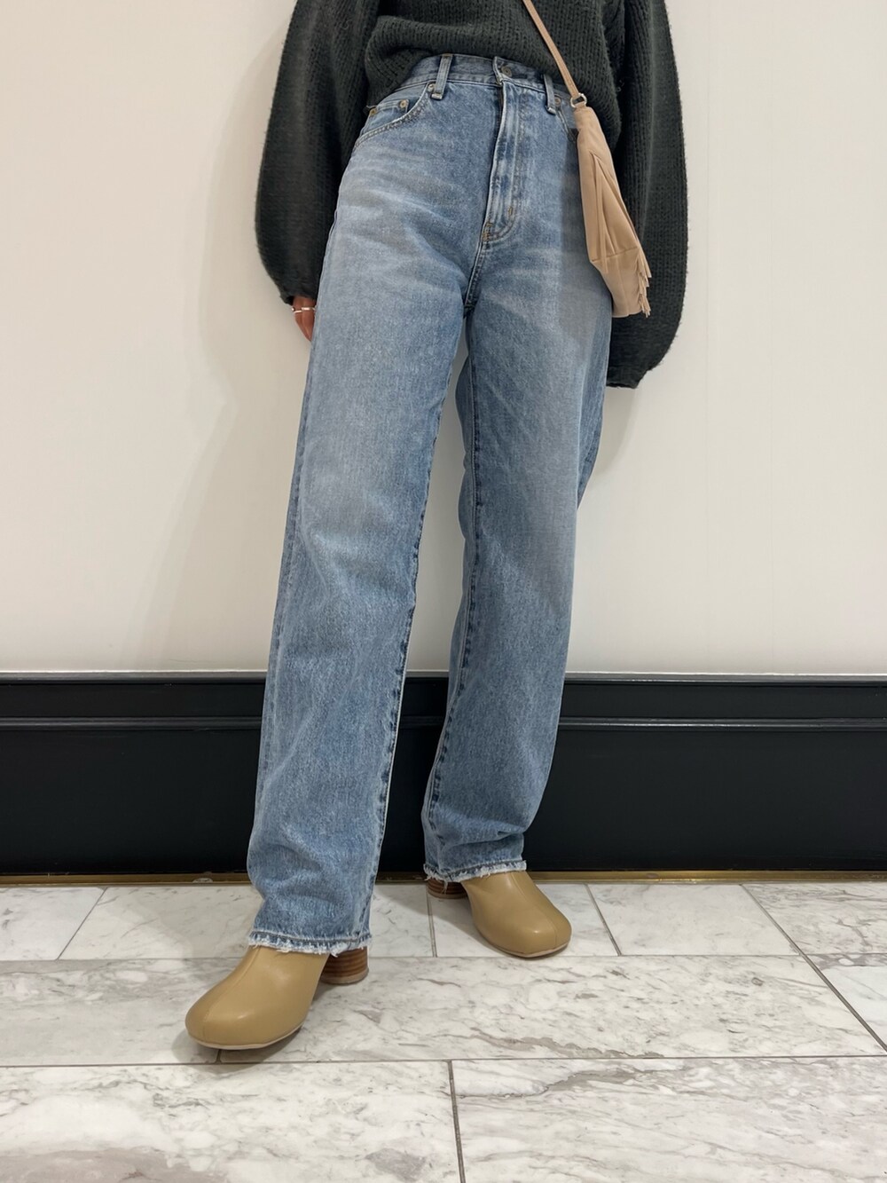 ブルー系のデニムパンツ、グレー系のニット/セーター、ベージュ系のブーツを着用したレディースの秋コーディネートの5枚目の写真